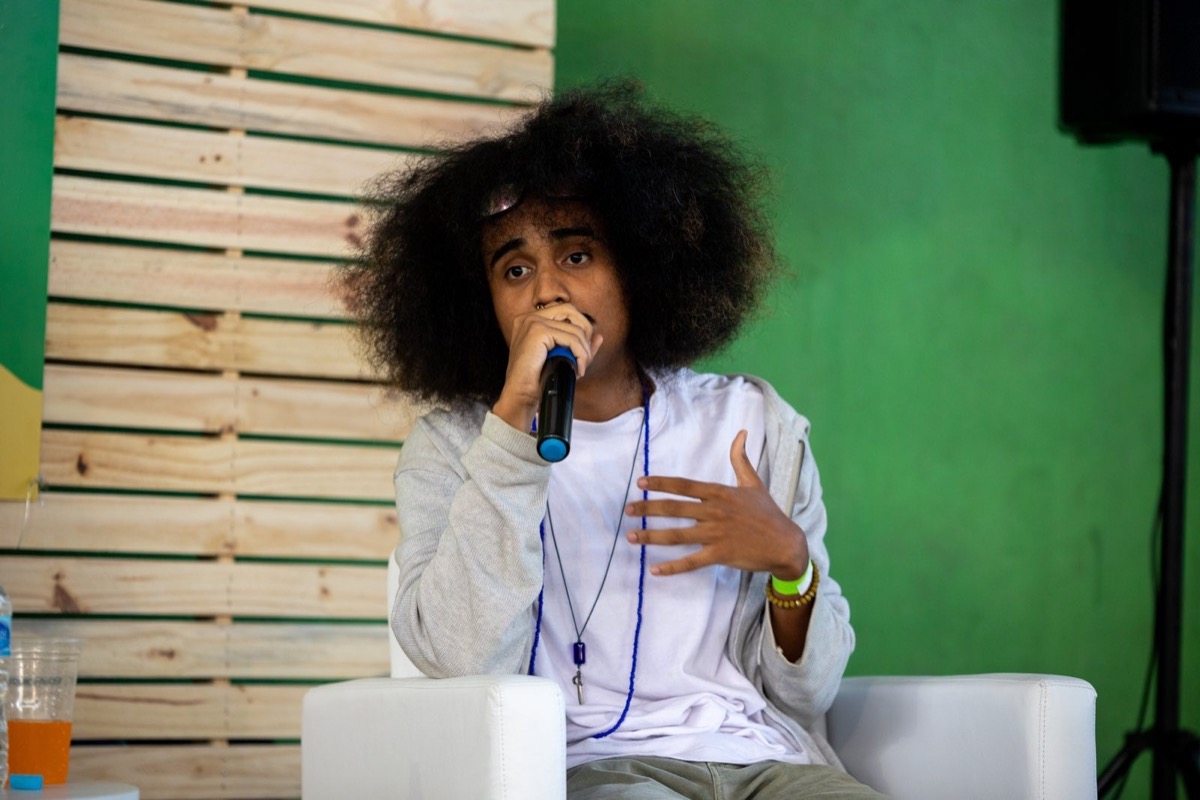 Raffael sentado com um microfone, falando durante uma mediação.