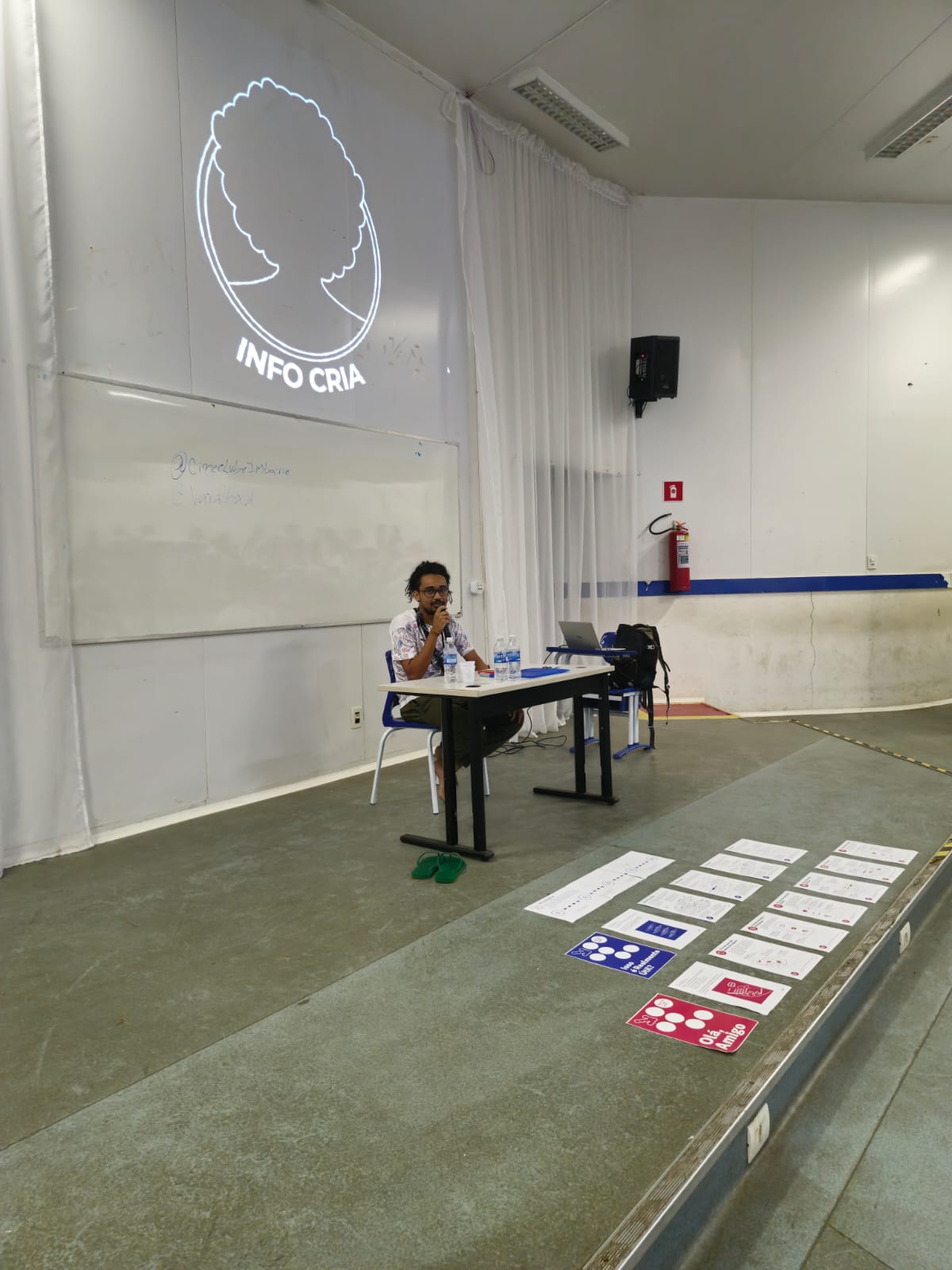 mediação da oficina, com projeção da InfoCria e materiais de atividade dispostos no chão.